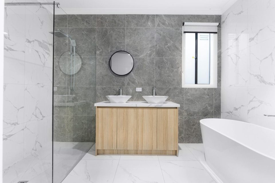 Modern bathroom remodeling reference with dual sinks, marble tile, and glass shower.