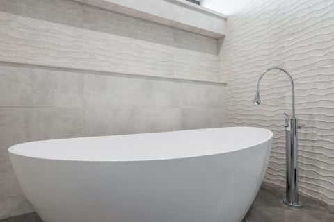 Bathroom remodel reference with stone walls, tub, and chrome faucet.