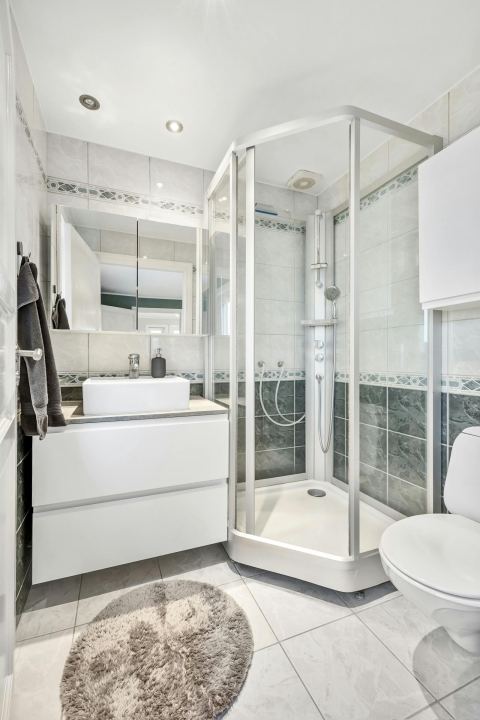 An elegant bathroom with a glass shower, white fixtures, and tile flooring.