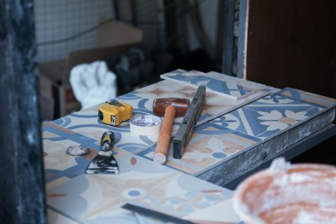 Flooring and tile installation reference with tools and tile on a construction surface.