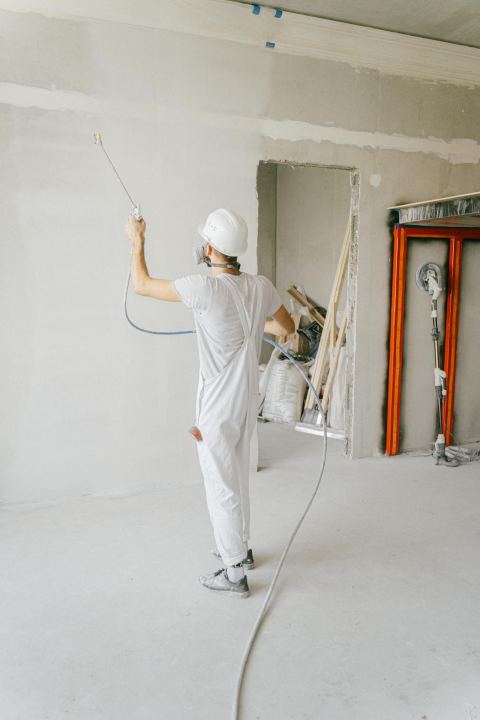 A worker applying primer to an interior wall during renovation.