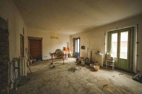 A sunny room under renovation with construction materials and open floor space.