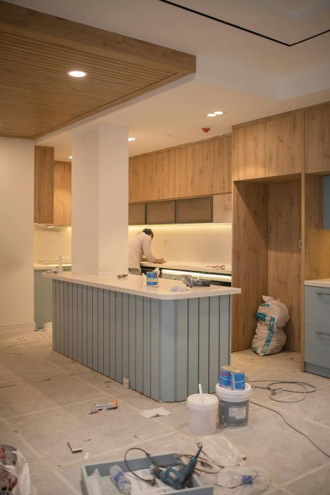 A modern kitchen under renovation with tools and cabinets in progress.
